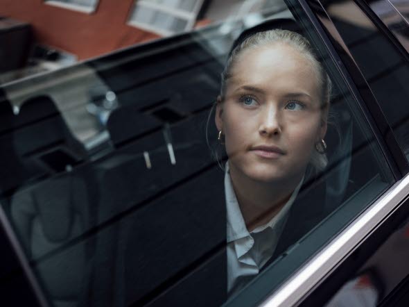 Bild på en ung kvinna som sitter i en bil och tittar ut genom bilfönstret.