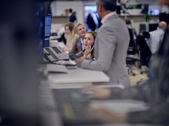 Image of a woman talking on the phone in front of computers at office.
