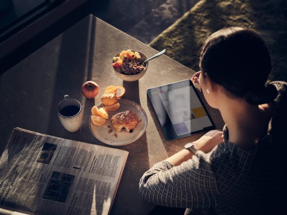 A woman having breakfast watching her tablet A woman having breakfast watching her tablet