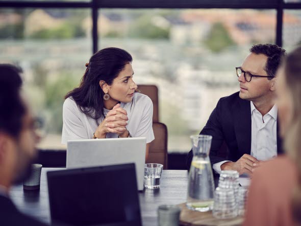 Image of a woman and a man talking by a meeting table at an office.