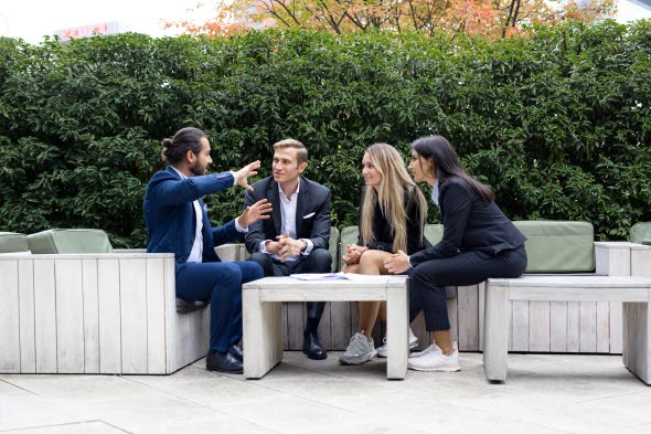 Bild på fyra kollegor som sitter utomhus och pratar med varann.