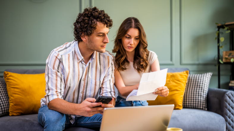 Ett par som sitter i en soffa och diskuterar sin ekonomi. (Arkivbild)
