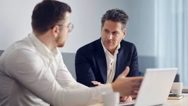 Two men sitting on a bench and looking at a  tablet discussing about Fixed income