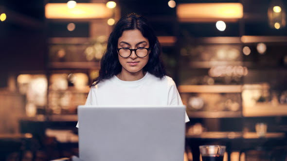 a girl in a white t-shirt working  at a laptop in the office